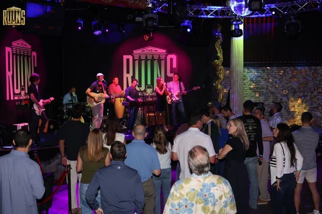 Live band performing on a nightclub stage, with people dancing in front of the stage.