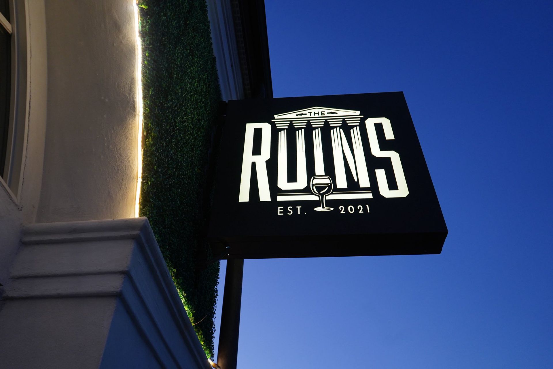 Black illuminated sign reading “RUNS” against a blue evening sky