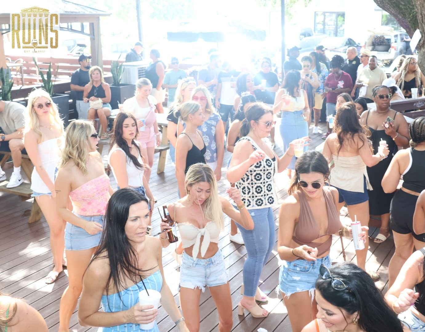 Crowded outdoor party with people dancing and socializing in bright sunlight
