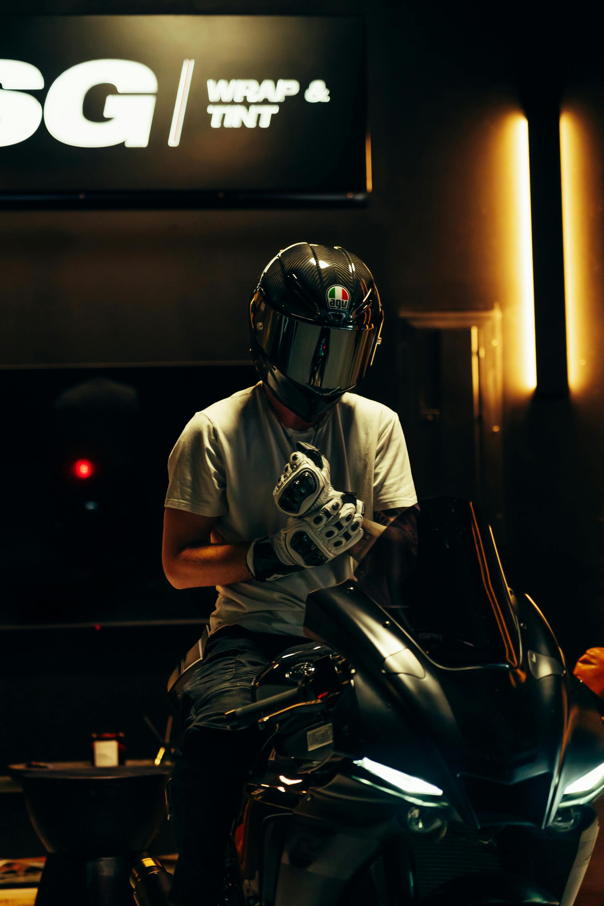 A man is sitting on a motorcycle in front of a sign that says wrap and tint.