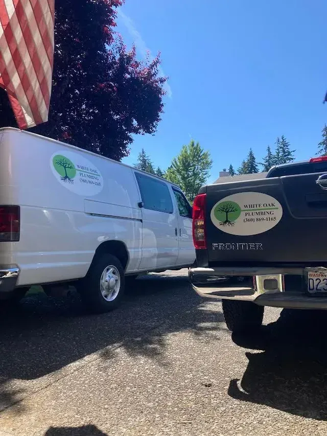 A white van and a black truck are parked next to each other in a parking lot in Vancouver, WA