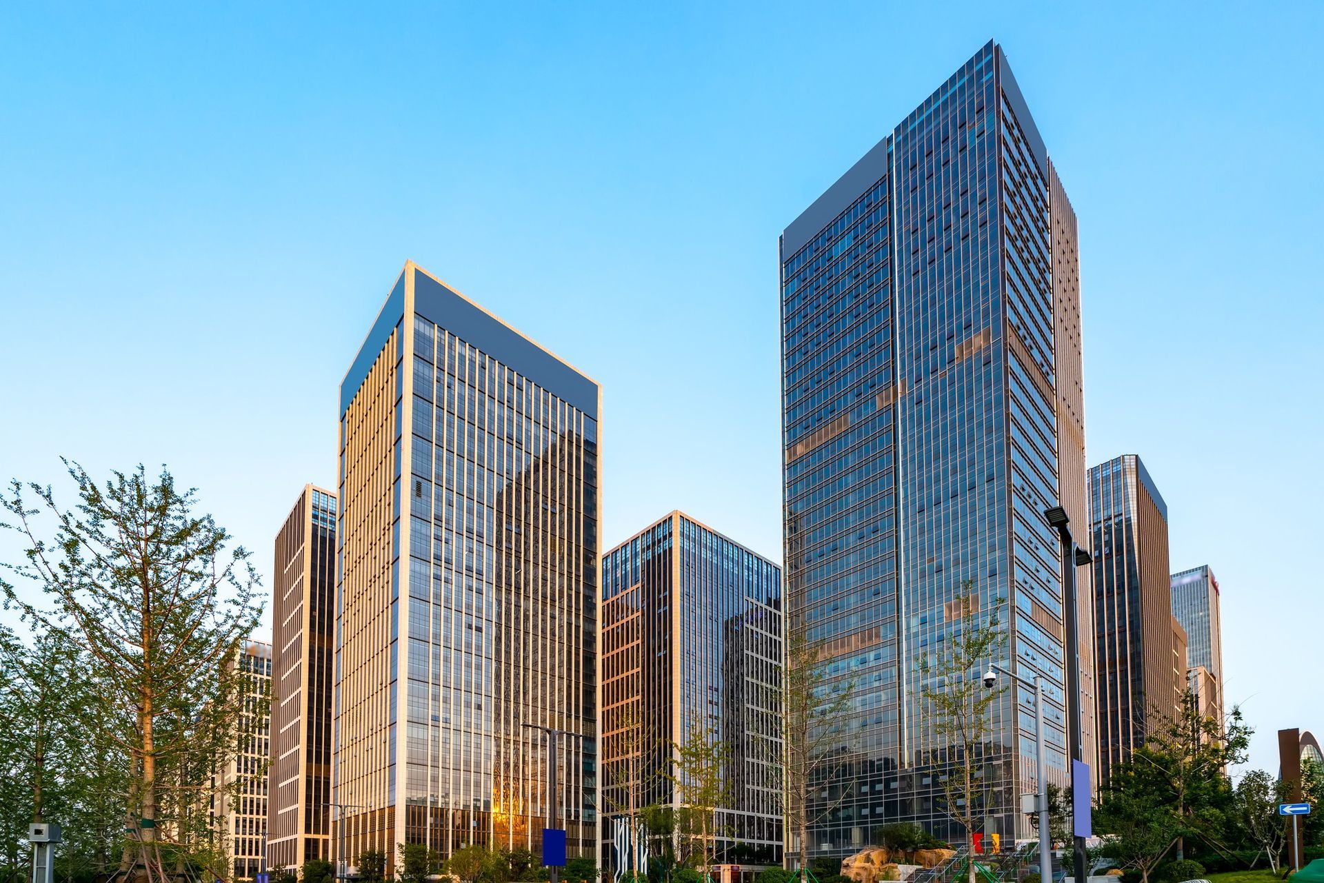 Modern skyscrapers with glass facades against a clear blue sky.