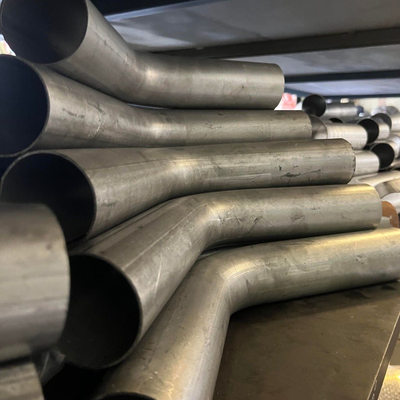 Bent Metal Pipes Stacked on a Shelf — Aitkenvale Exhausts & Towbars Pty Ltd In Aitkenvale, QLD