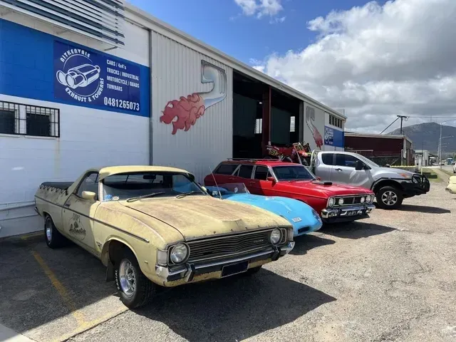 Four Classic Cars Parked Outside a White Garage — Aitkenvale Exhausts & Towbars Pty Ltd In Aitkenvale, QLD