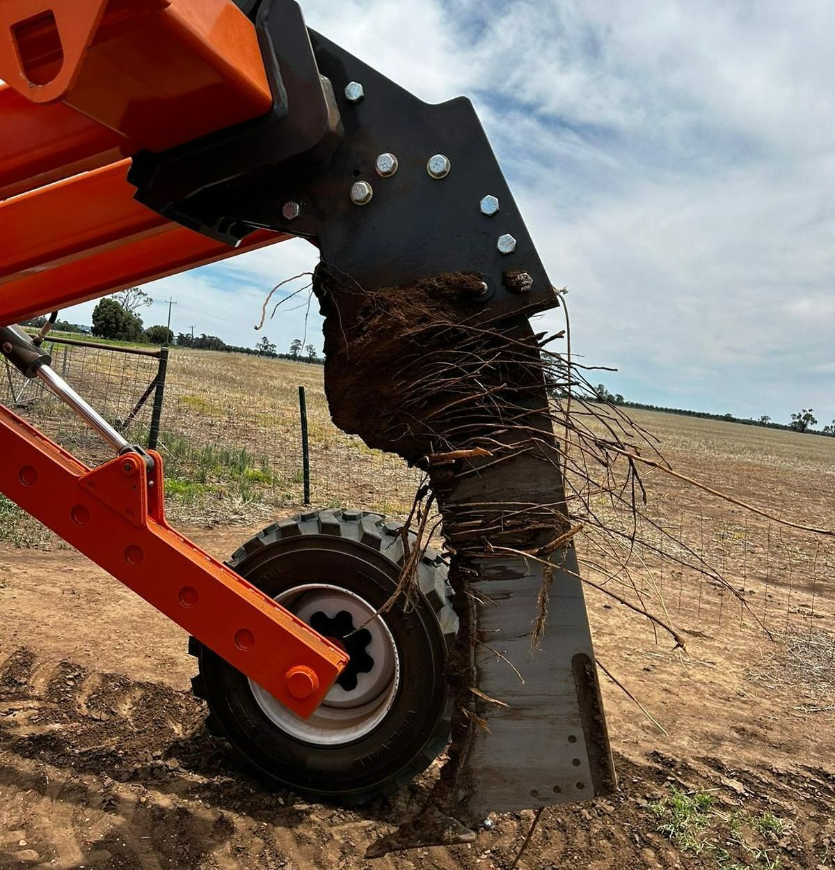 A TTQ Tree Line Ripper after it has been pulled by a tree line of a field, removed roots cover the tyne.