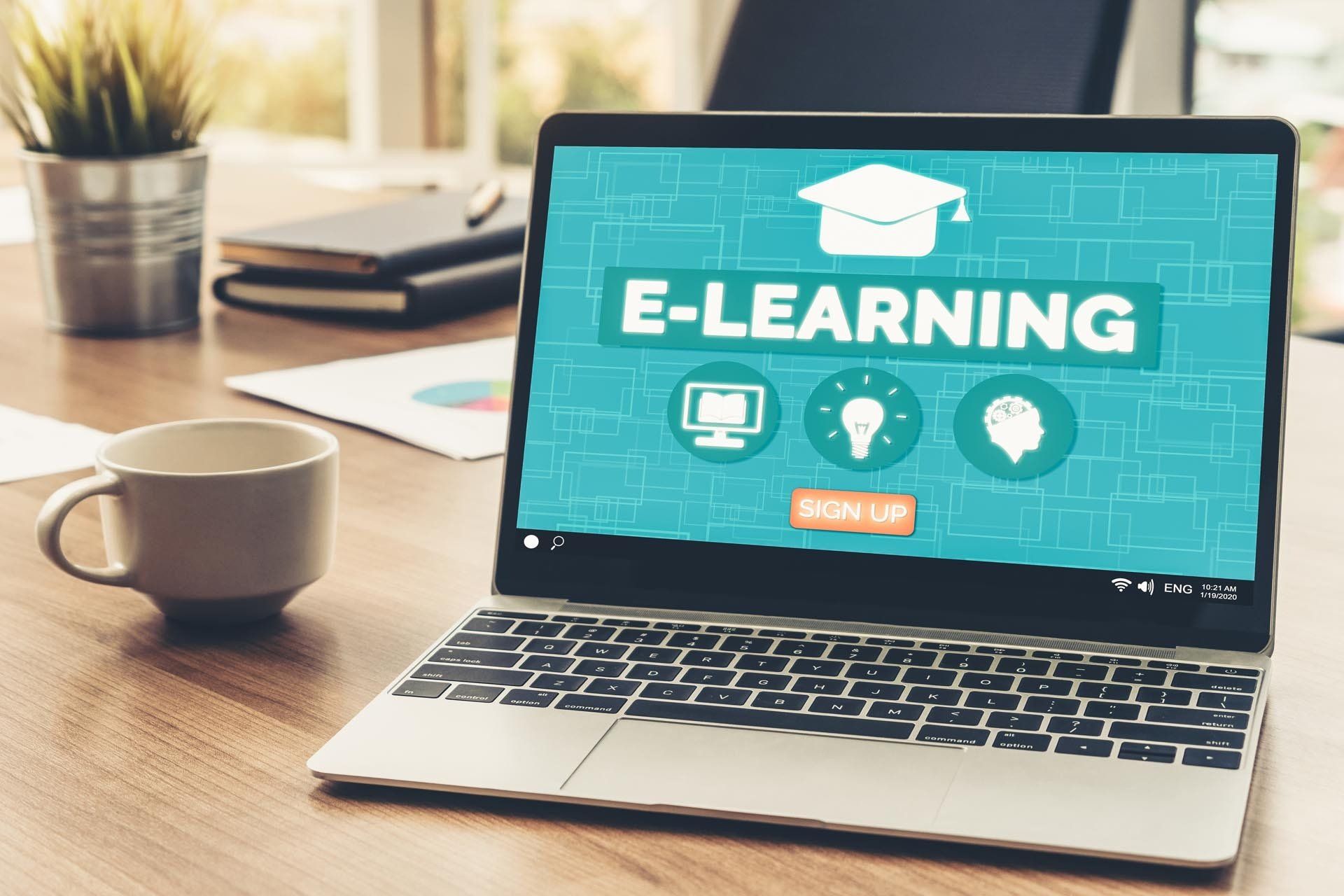 Auf einem Laptop ist ein Bildschirm mit der Aufschrift „E-Learning“ geöffnet.