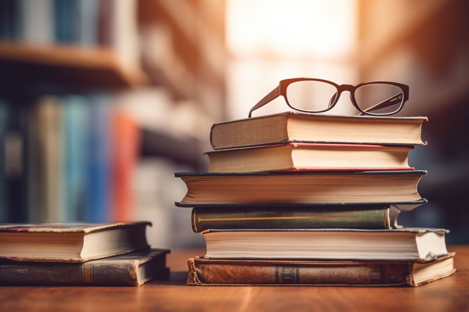Ein Stapel Bücher mit Gläsern darauf auf einem Holztisch.