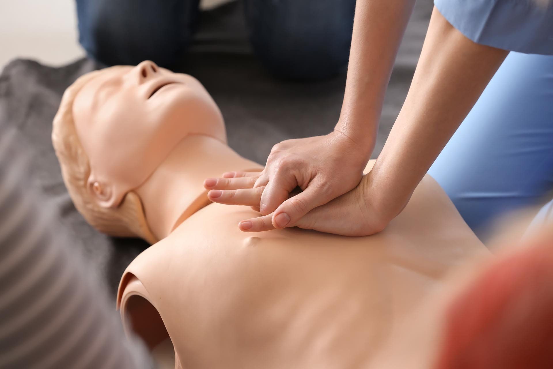 Eine Person gibt einer Schaufensterpuppe eine Herzmassage.