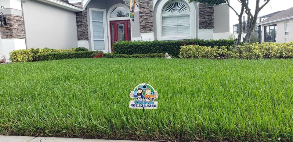 Lawn sign in front of a suburban house with a red front door and manicured grass.