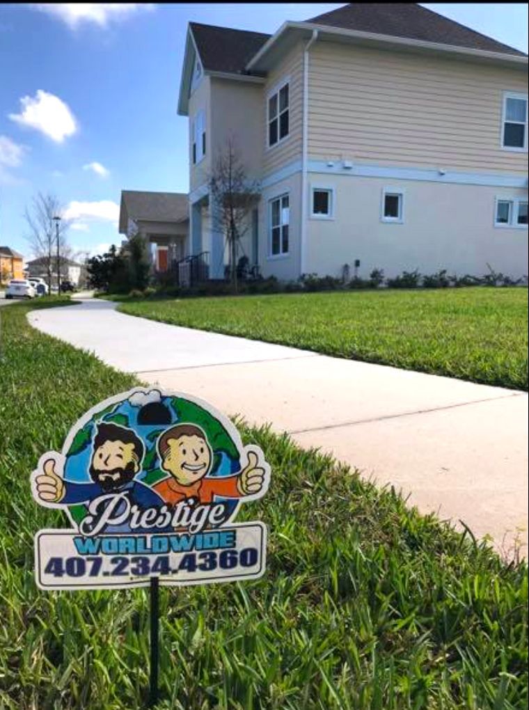 Prestige Worldwide lawn sign in front of a beige apartment building and sidewalk