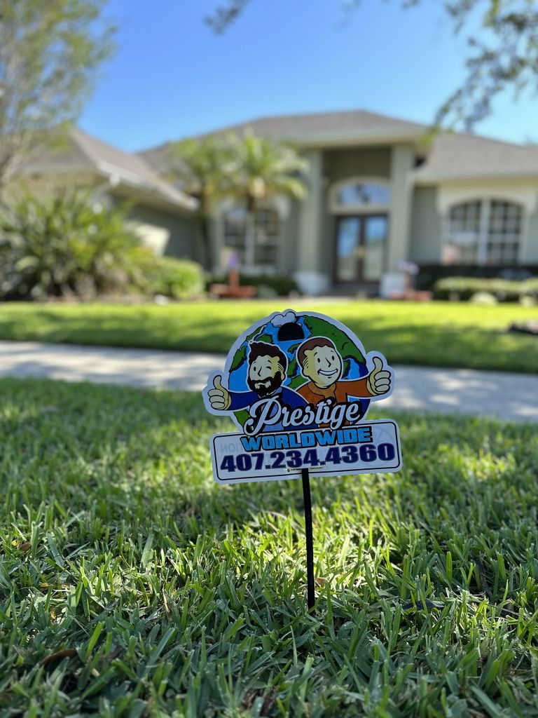 Lawn sign with a colorful landscaping logo and phone number in front of a house