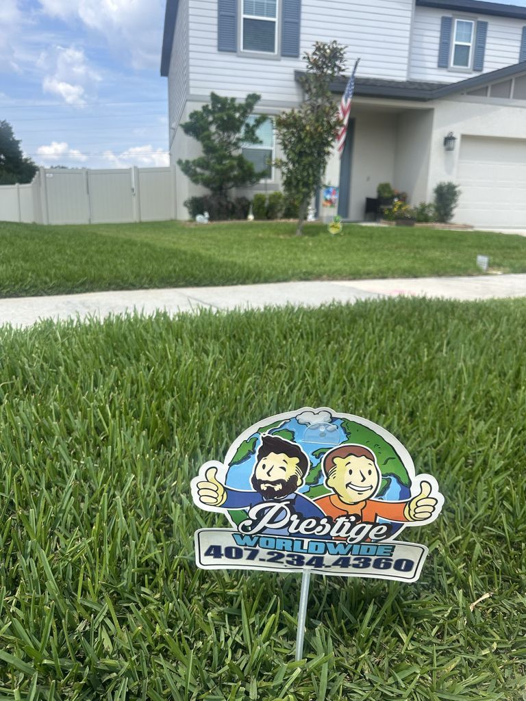 Custom lawn sign on a front yard beside a sidewalk, with a house, grass, and an American flag in the background