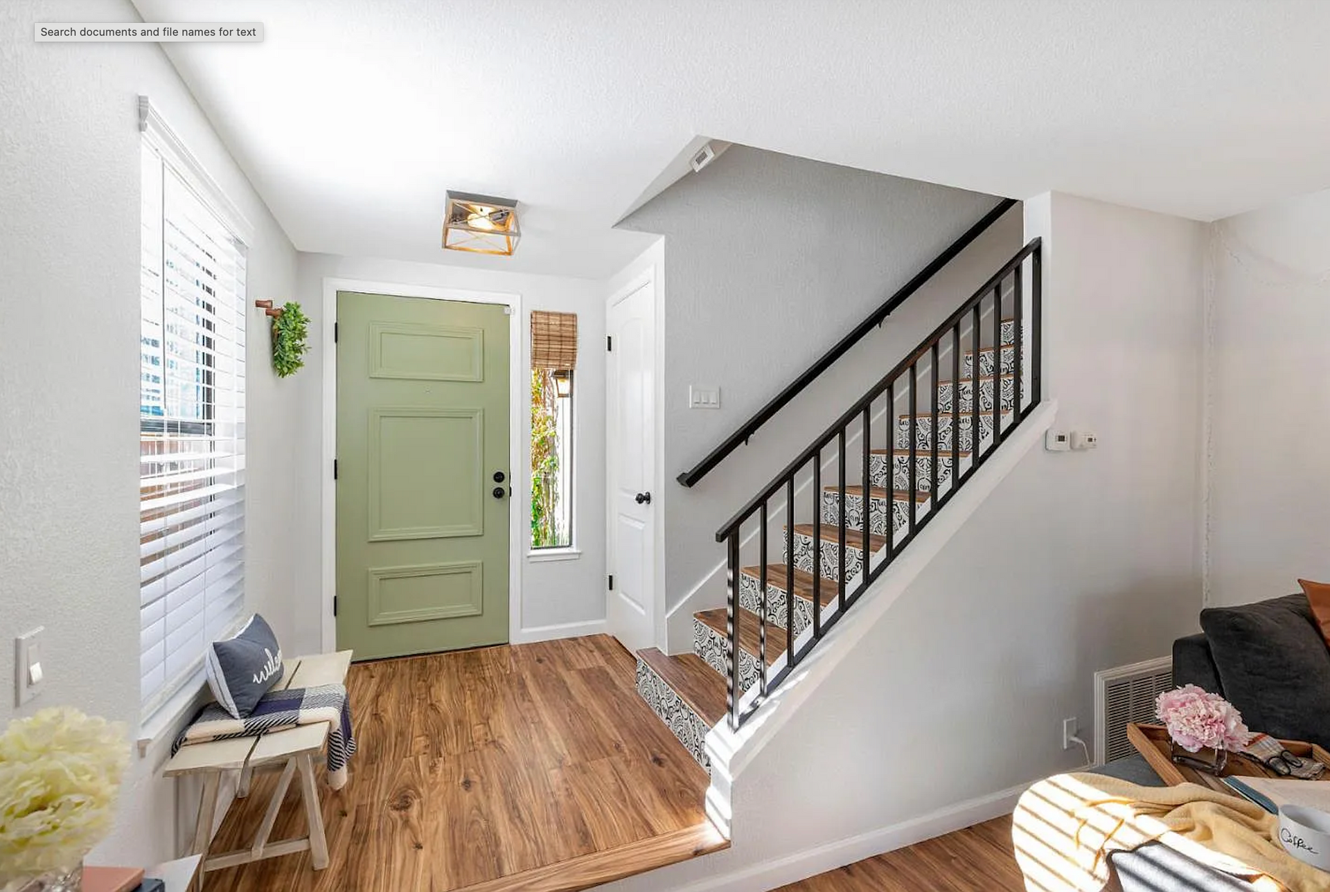 Entryway with a green door, staircase, and wooden floors.