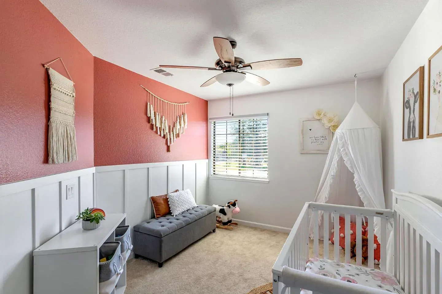Nursery with red accent wall, white wainscoting, crib, and decorative items.