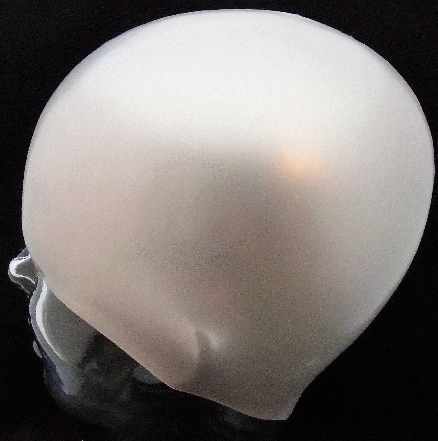 A white swimming cap is on a mannequin head