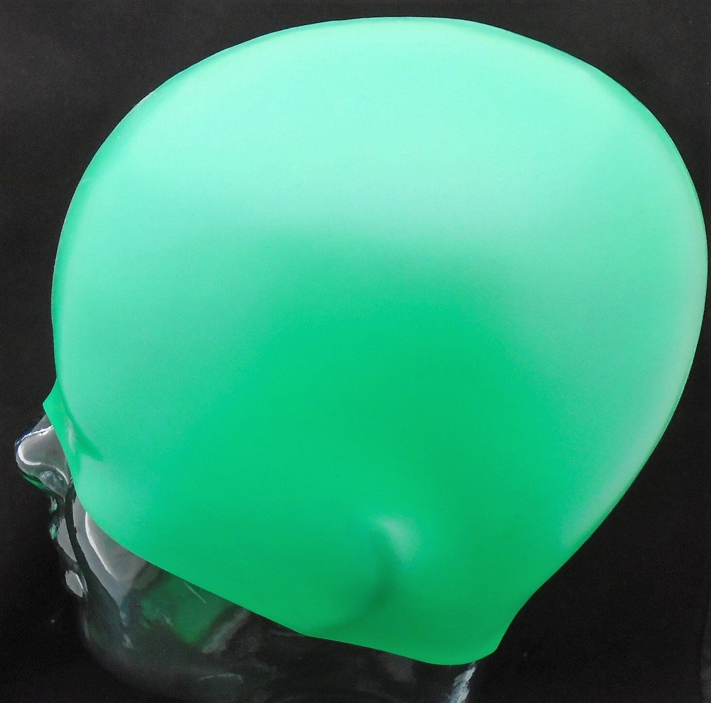 A green swimming cap is on a mannequin head