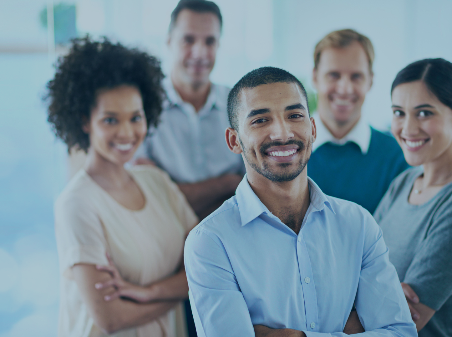 Five smiling coworkers standing together in an office setting