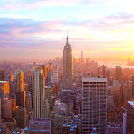 Sunset skyline of Manhattan with the Empire State Building glowing in warm pink and orange light