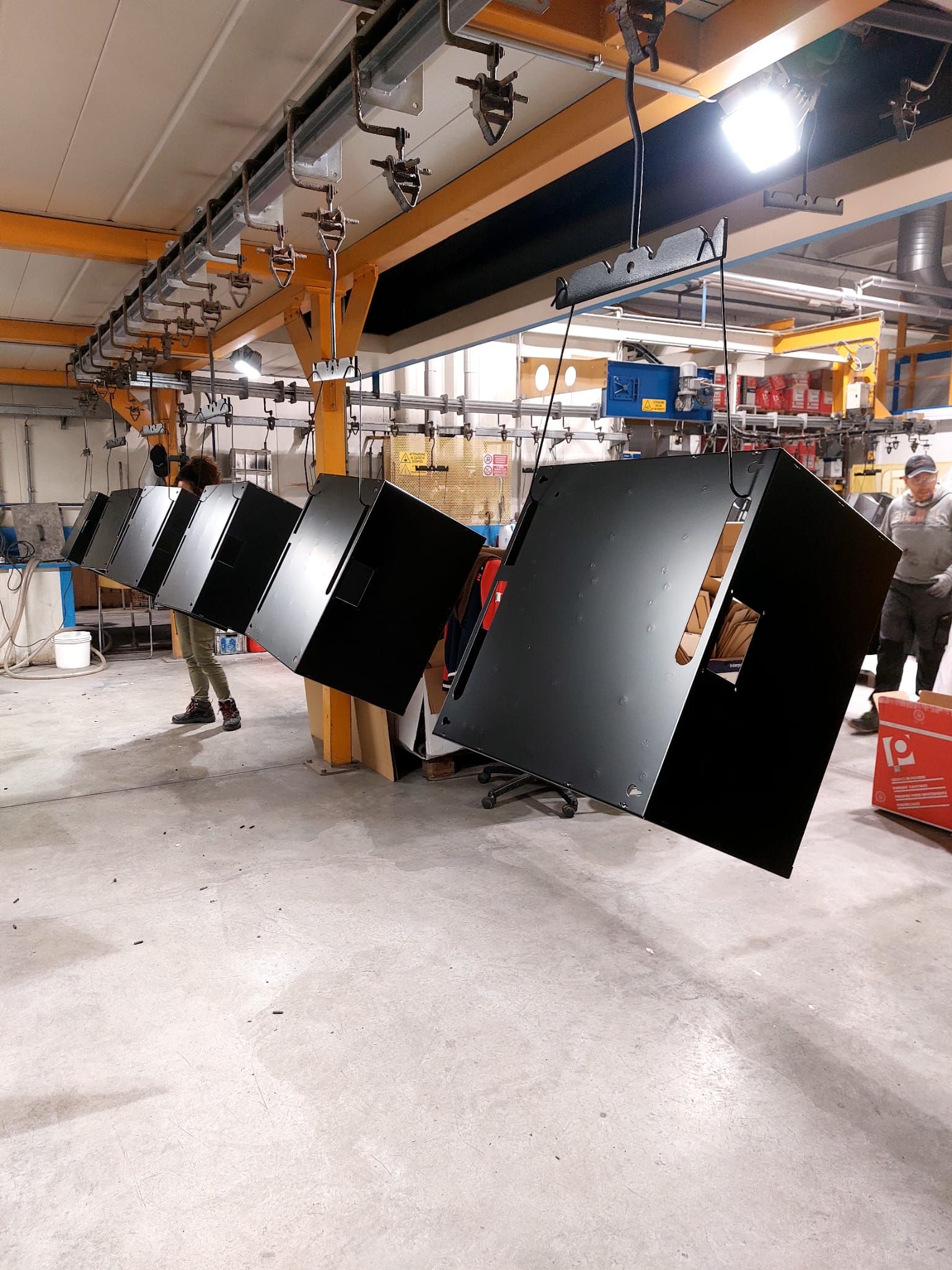 Operai che trasportano grandi pannelli neri in un'officina industriale.
