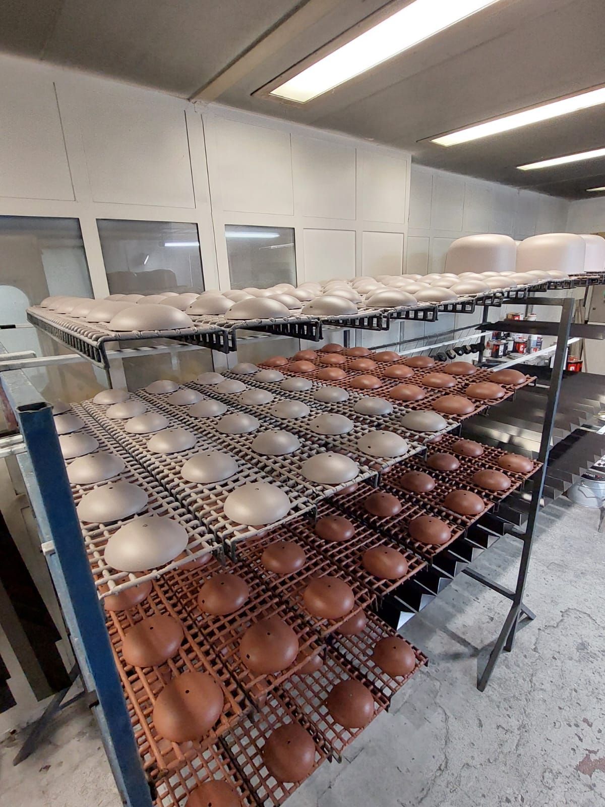 File di ciotole di ceramica su scaffali in un luminoso laboratorio o in una stanza adibita a forno.