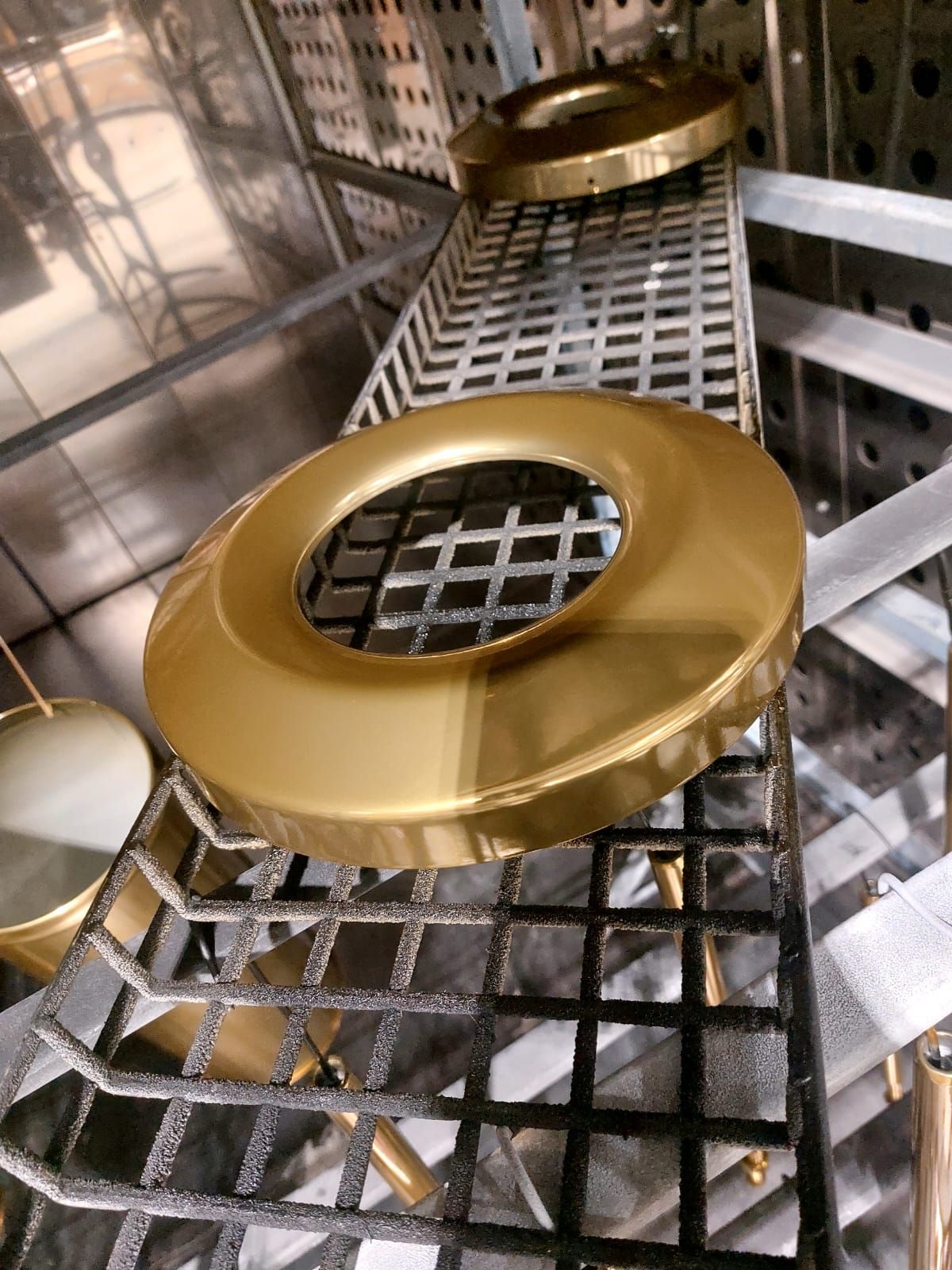 Componenti circolari dorati su un nastro trasportatore metallico in un ambiente industriale.