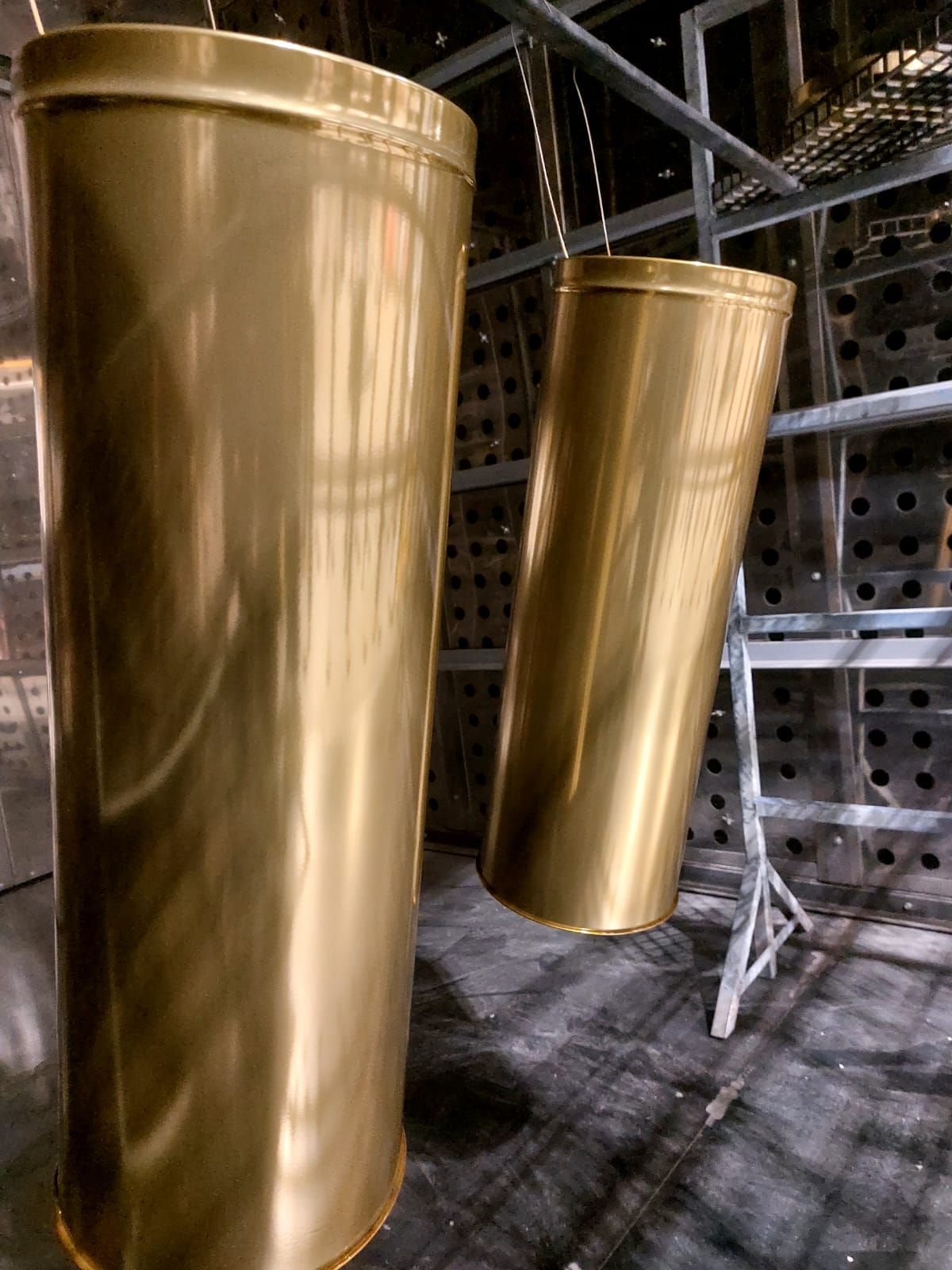 Due grandi fusti cilindrici color oro in un ambiente industriale adibito a magazzino.