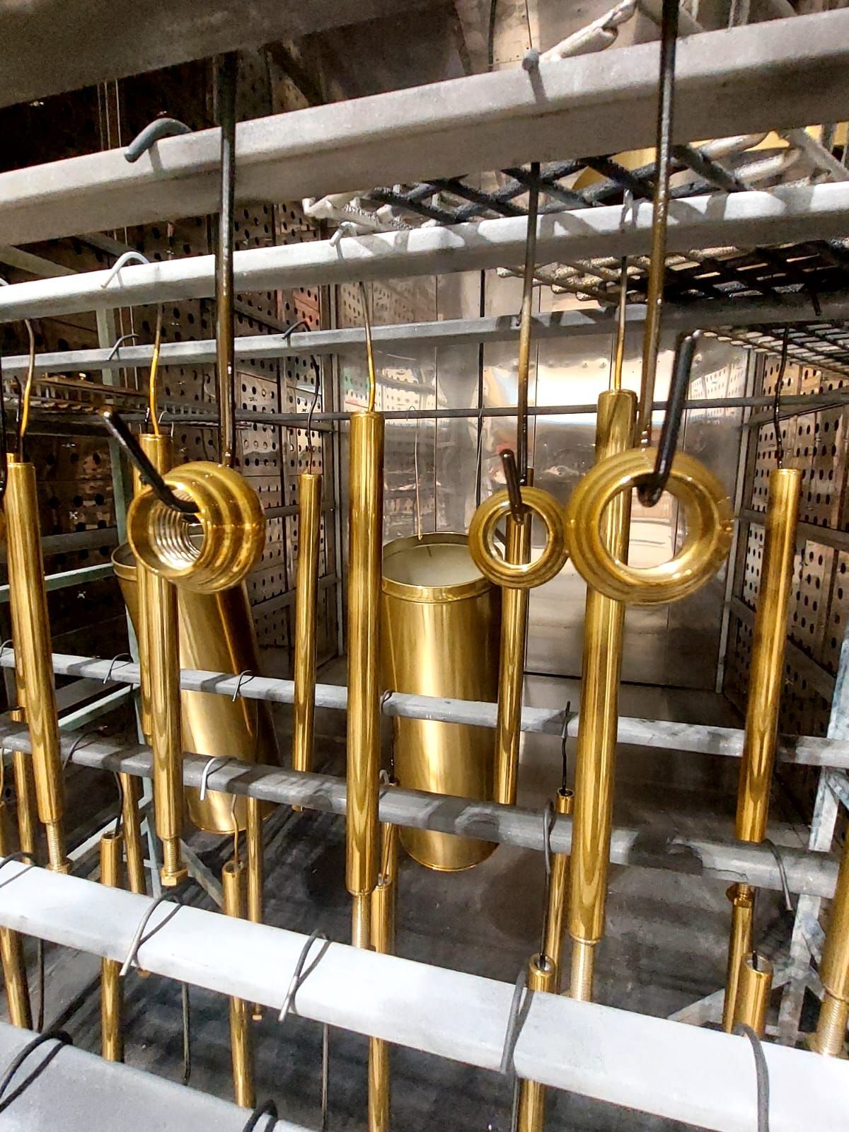 Tubi e anelli circolari in metallo dorato installati in un contesto di costruzione industriale.