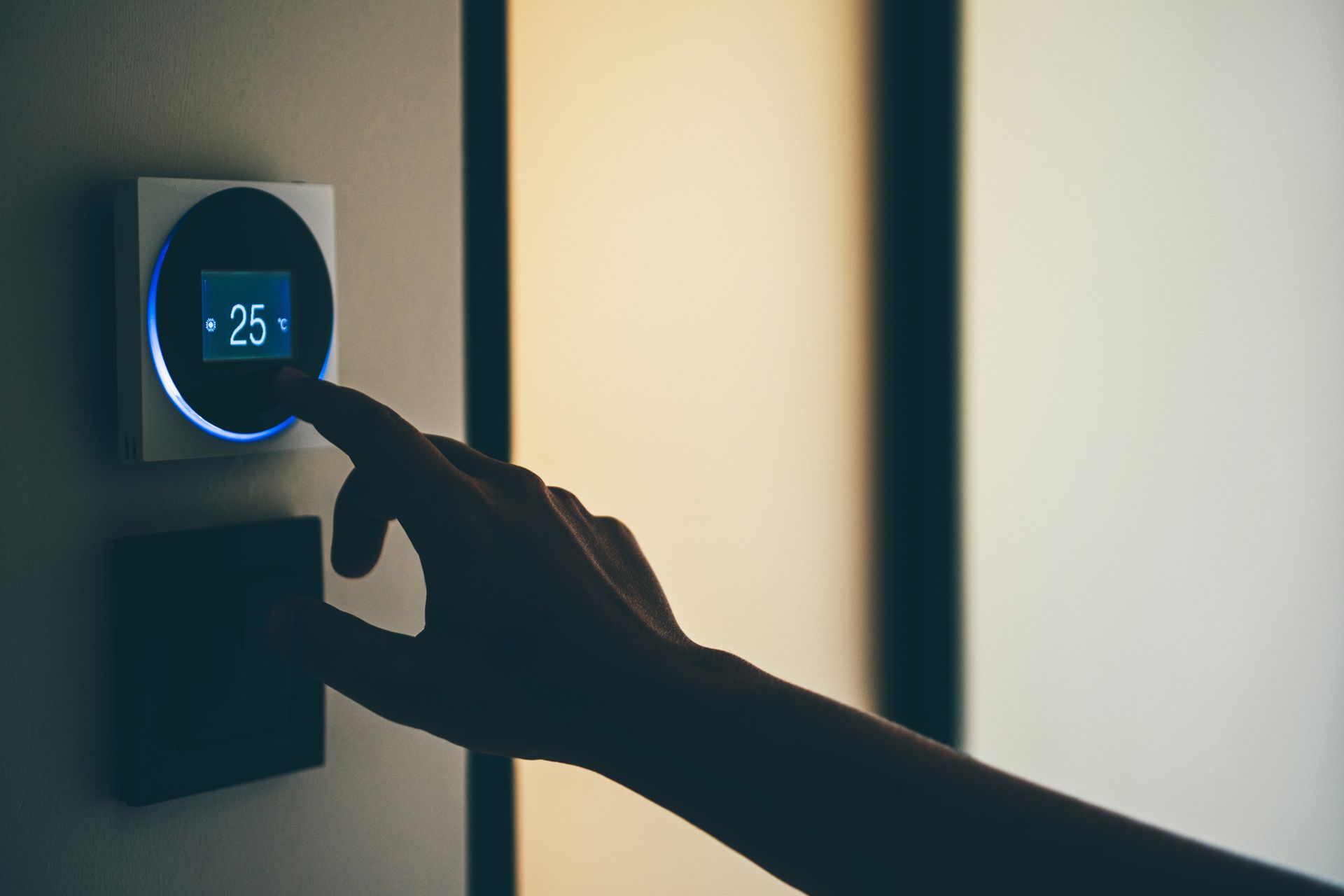 A person is pressing a button on a thermostat.