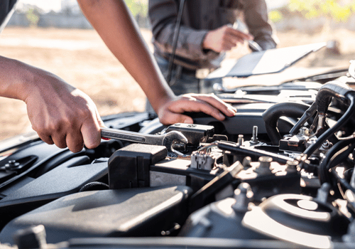Mechanic using tools to repair a car engine in a garage