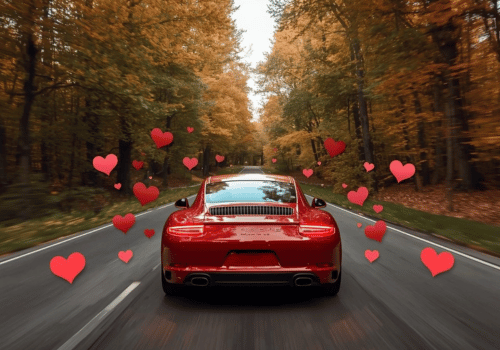 Red Porsche driving through an autumn forest road with floating heart graphics.