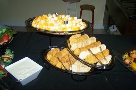 Buffet table with pastries, cheese cubes, breadsticks, and a bowl of dip.