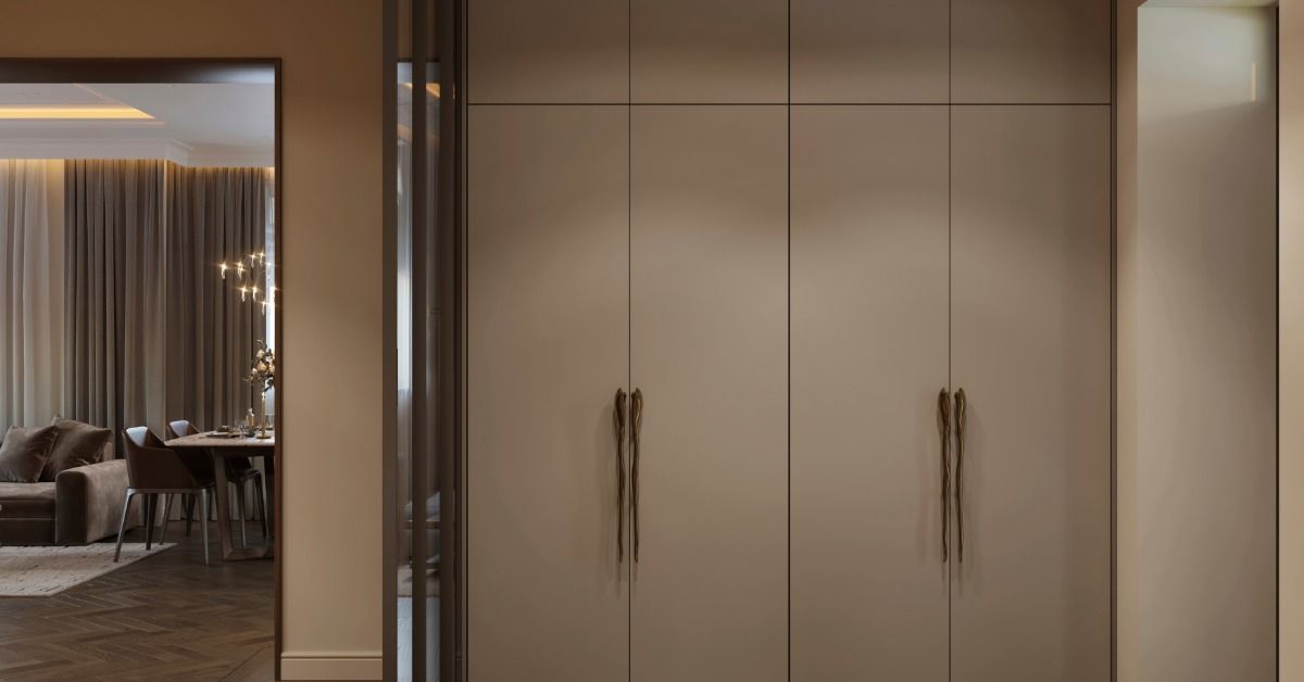 A hallway near a living area features a wall of tall built-in cabinets, recessed ceiling lights, and warm cove lighting.