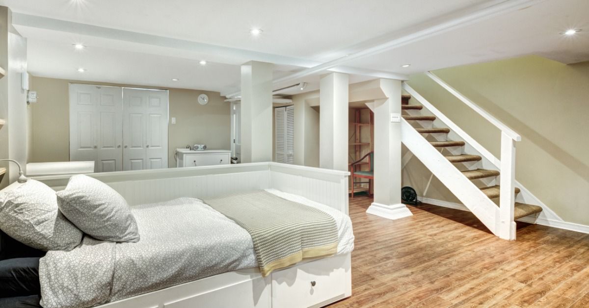 A carpeted staircase leads to a finished basement. The room has recessed lights and a bed with built-in drawers.
