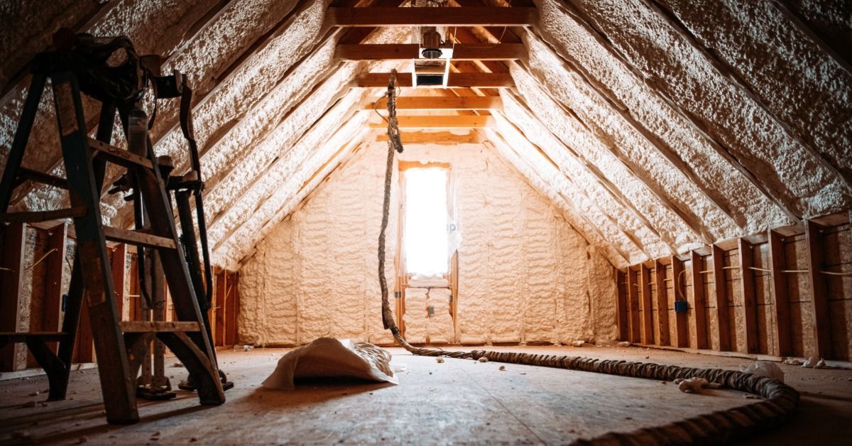 Spray foam insulation covers the sloped roof deck and far wall of an unfinished attic.
