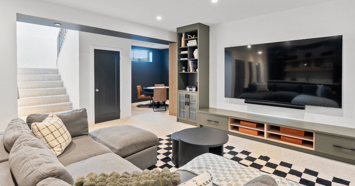 A room features a large gray sectional sofa facing a wall-mounted television surrounded by built-in cabinetry.