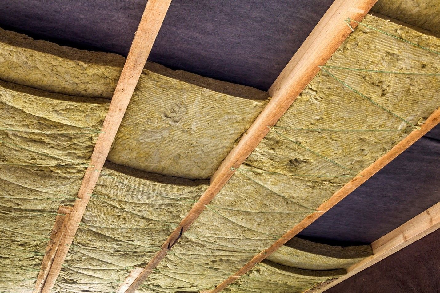 An empty room with wooden beams and insulation on the ceiling.
