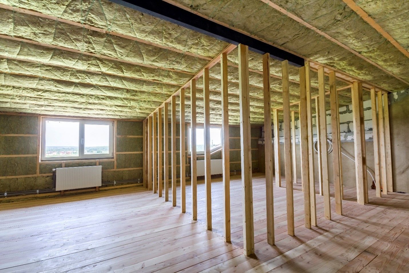 An empty room with wooden beams and insulation on the ceiling.