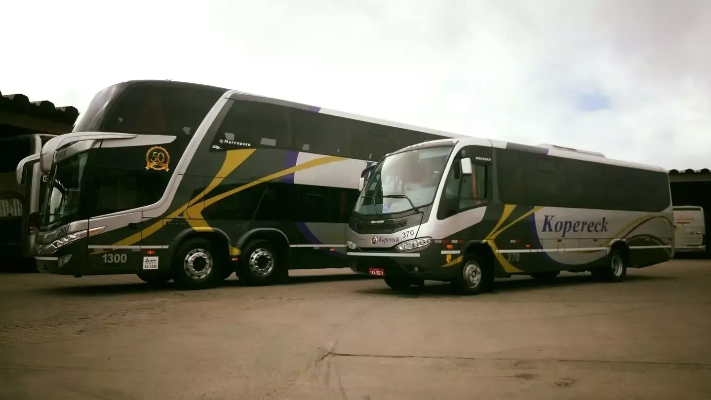 Dois ônibus estão estacionados um ao lado do outro em um estacionamento.