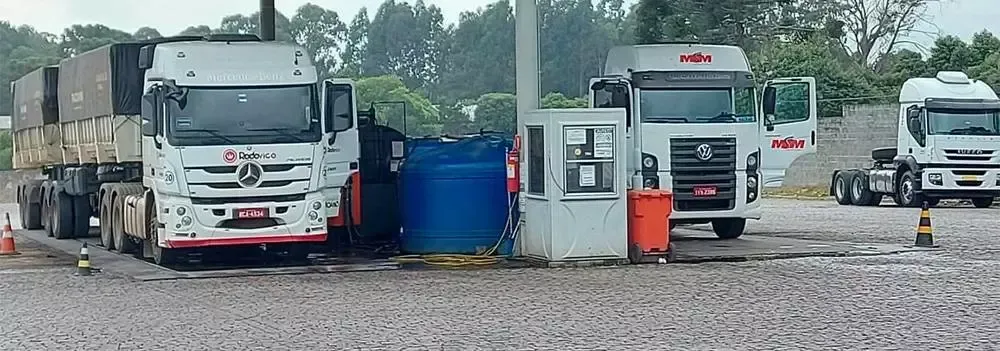 Uma fileira de caminhões está estacionada em um estacionamento de cascalho.