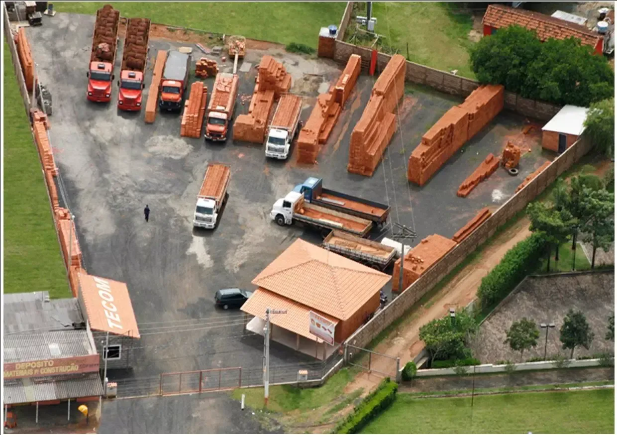 Uma vista aérea de um pátio de tijolos com caminhões e tijolos