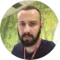 Um homem com barba está usando um cordão em volta do pescoço.