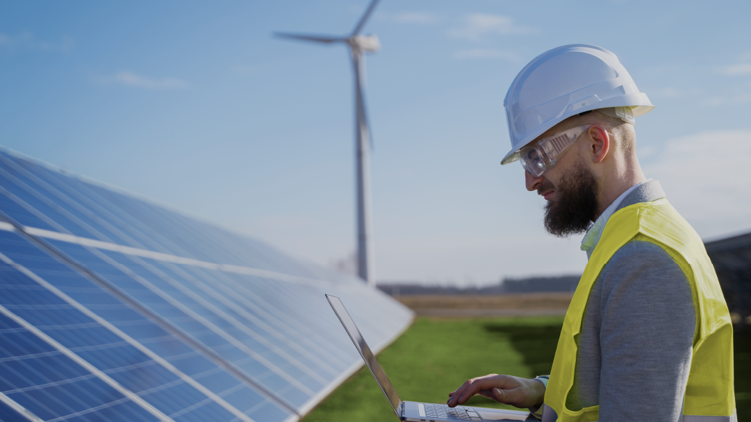 Um homem com capacete está parado em frente a um painel solar.