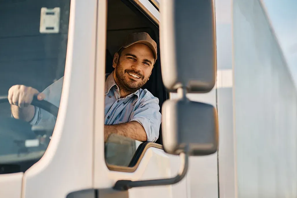 Um homem está sentado no banco do motorista de um caminhão.