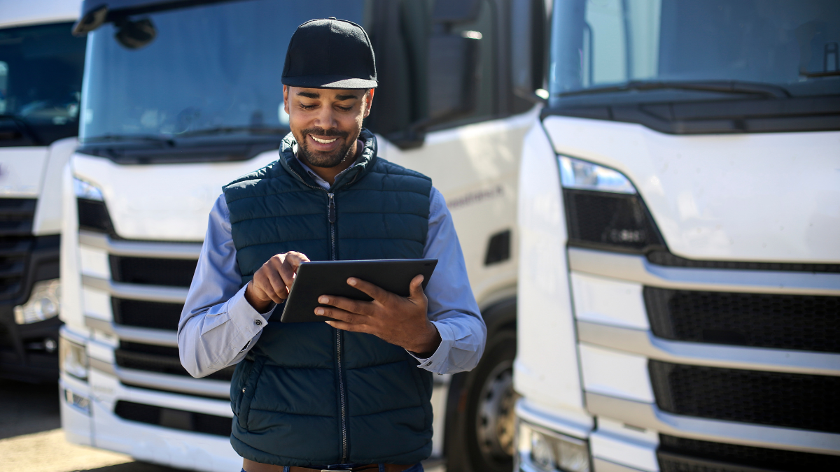 Gestor de frota usando tablet com plataforma de controlador de combustível em pátio com caminhões .
