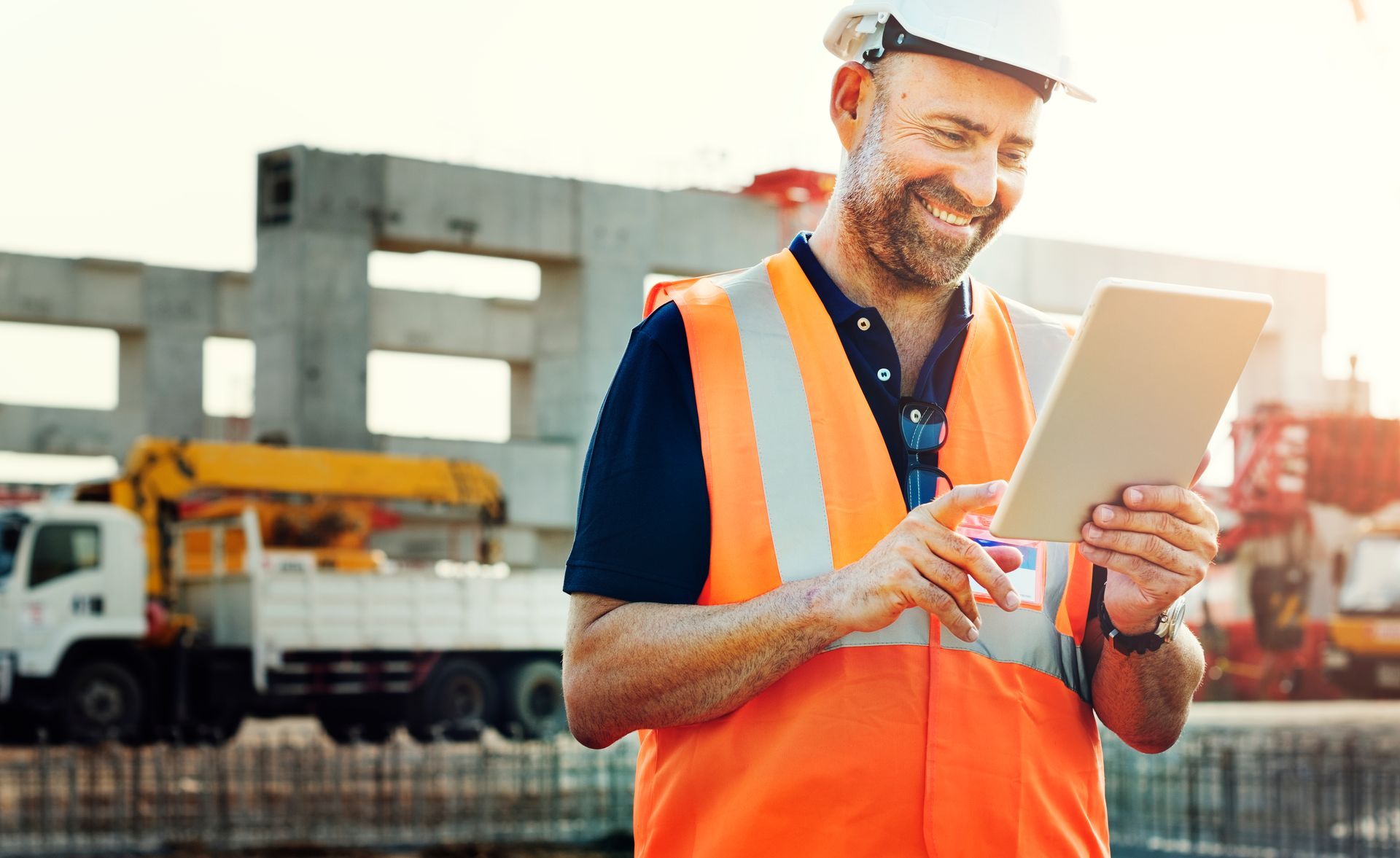 Engenheiro no canteiro com tablet para gestão de obra, planejamento e rastreabilidade.