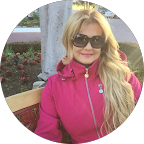 Portrait of Aleimy Acosta wearing sunglasses and a pink jacket outdoors
