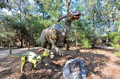 A group of dinosaurs are standing next to each other in a park.