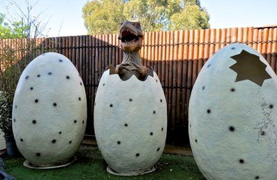 A statue of a dinosaur coming out of an egg