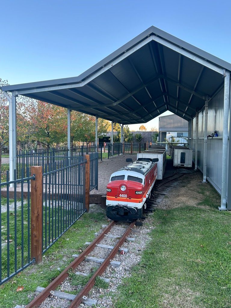 A small train is sitting on a train track under a covered area.