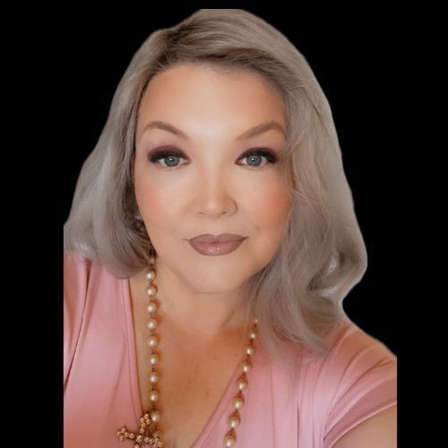 Portrait of a woman with blonde hair, pink top, and pearl necklace against a black background